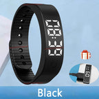 Black digital fitness tracker with charging cable on a blue background
