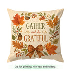 A square cream throw pillow with a fall-themed flat print featuring the text 'GATHER and be GRATEFUL' surrounded by orange and green autumn leaves, acorns, berries, and a plaid bow. Text below reads '2d flat printing, Non-real embroidery.