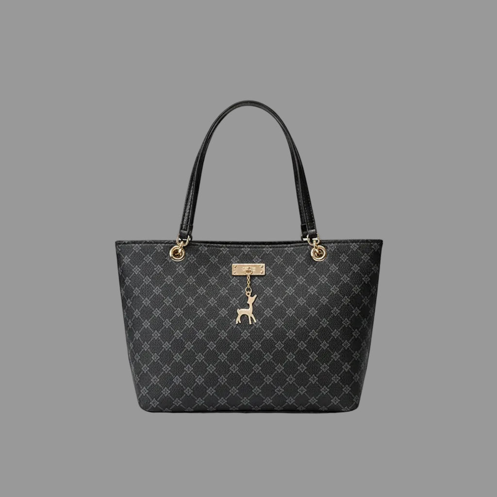 Black patterned handbag with a dog charm on a wooden surface