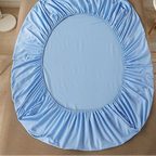 Blue fitted sheet on a bed with 'vave' branding.