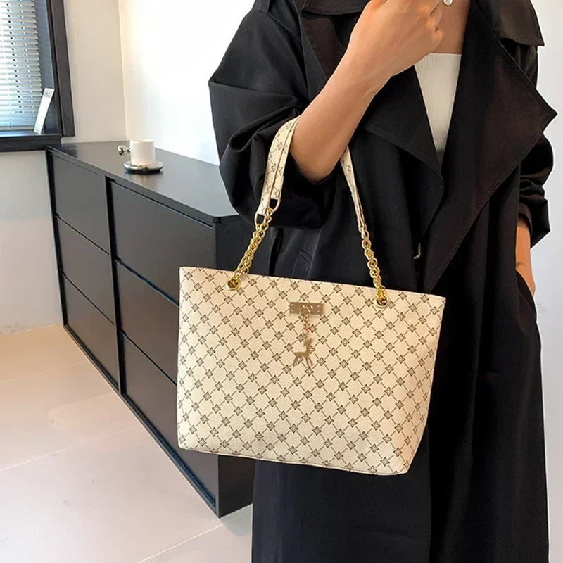 Person holding a beige handbag with a pattern, wearing a black outfit, in an indoor setting.