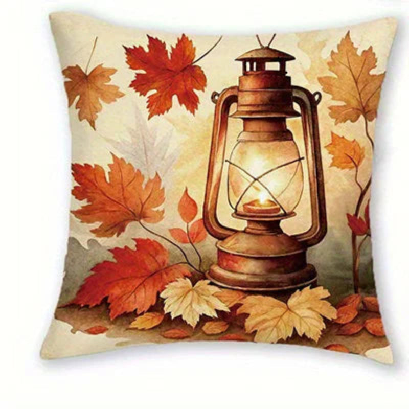 Square decorative throw pillow featuring an autumn-themed print with a glowing vintage lantern and scattered red, orange, and beige leaves on a cream background.