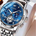 Silver watch with blue face on a white cushion, brand 'OLEVS' visible