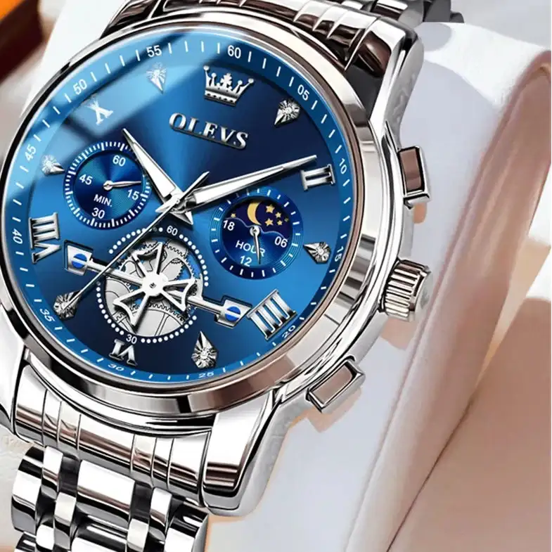 Silver watch with blue face on a white cushion, brand 'OLEVS' visible