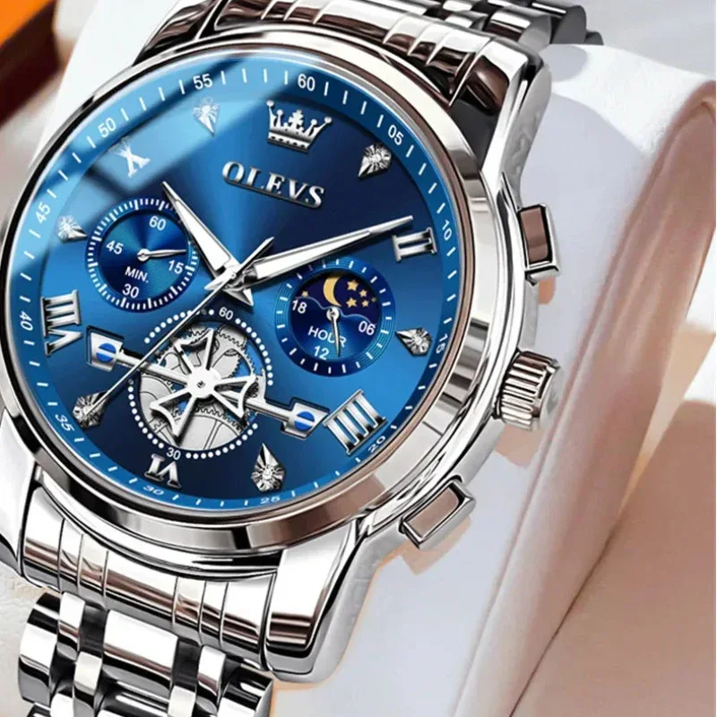 Silver watch with blue face on a white cushion, brand 'OLEVS' visible