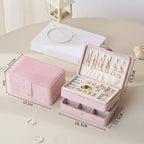 Pink jewelry box with jewelry items on a light surface, showing dimensions.