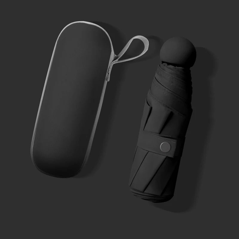 A black compact umbrella and its matching hard case on a dark gray background. The umbrella is shown partially folded, with a circular button closure and a loop handle, next to its elongated protective case with a white zipper.