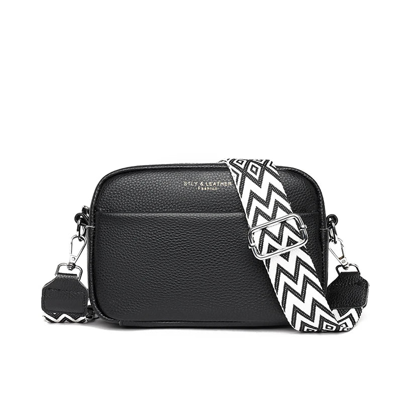 Black crossbody bag with a black and white zigzag strap on a white background