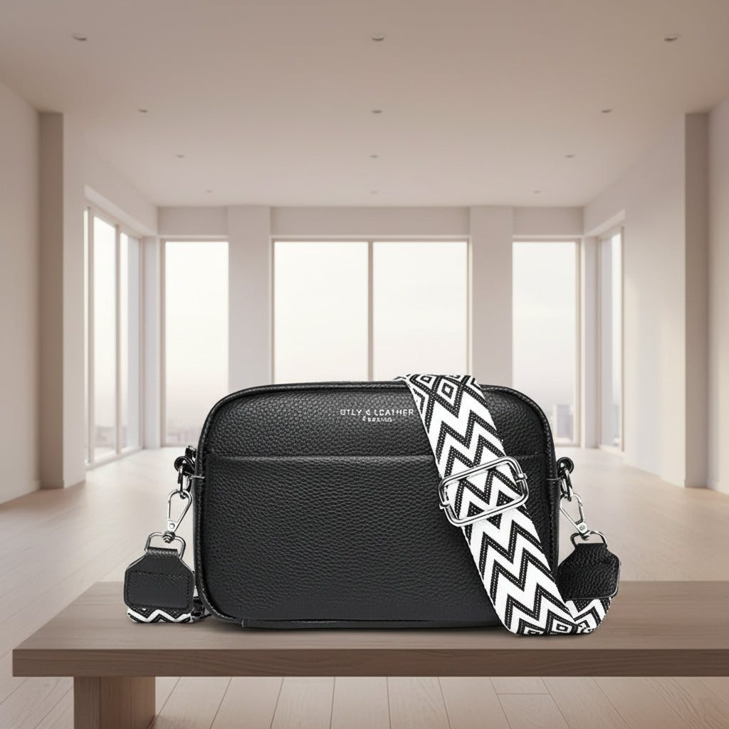 Black crossbody bag with a black and white zigzag strap on a white background