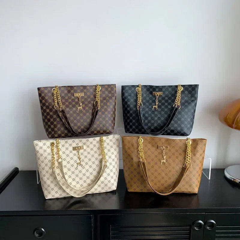 Four handbags in different colors on a black surface with a white background