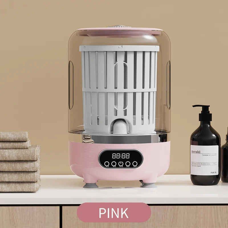 Pink and gray electronic device on a beige surface with towels and bottles in the background