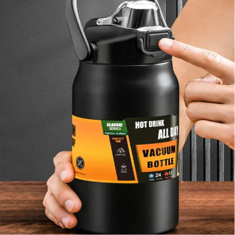 Black vacuum bottle with orange label held by a person on a wooden surface.