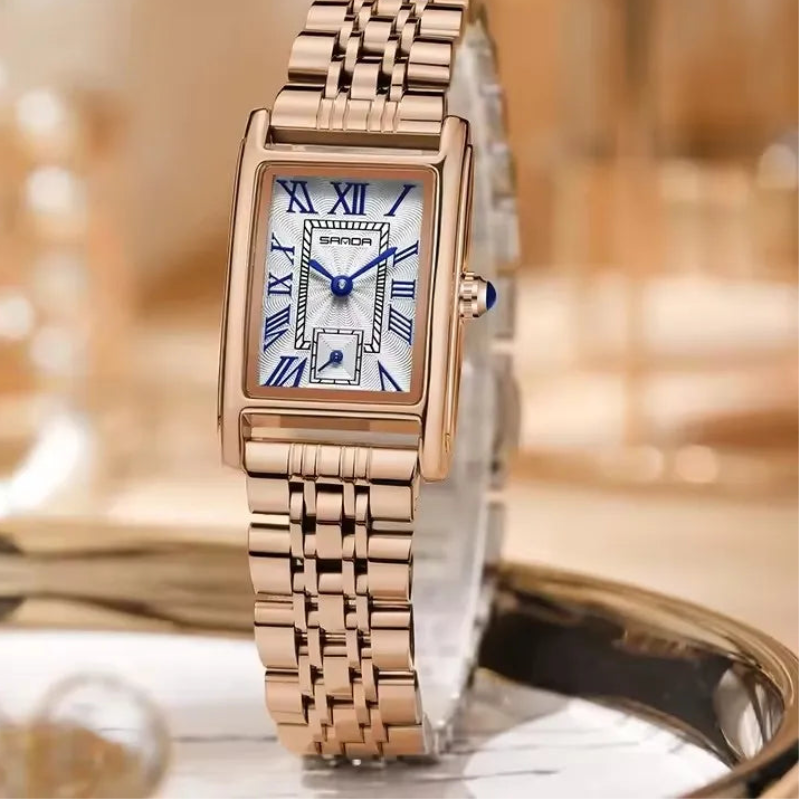 Rose gold watch with a blurred background featuring the brand 'SANDA'.