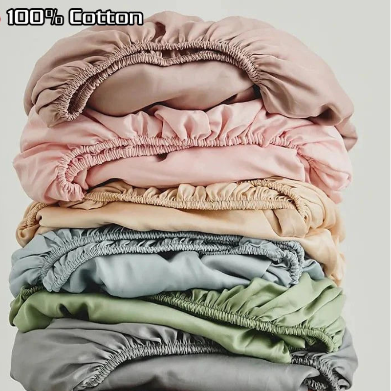 Stack of colorful fitted sheets on a wooden stool with '100% Cotton' text above.