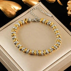 Gold and silver beaded bracelet on a gold box with a black background