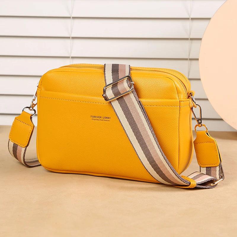Yellow shoulder bag with a striped strap on a beige surface