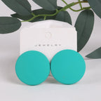 Turquoise earrings on a jewelry card with green leaves in the background