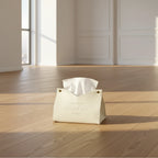 White wedge-shaped product on a wooden surface with a magazine and gold decorative item in the background.