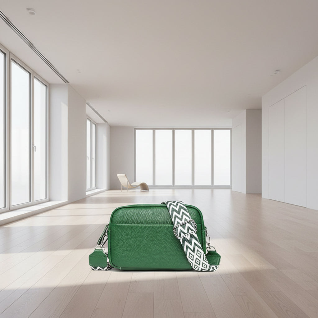 Green leather crossbody bag with a patterned strap on a white background