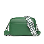 Green leather crossbody bag with a patterned strap on a white background