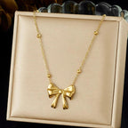 Gold bow necklace on a beige jewelry box