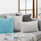 Gray sofa with textured throw pillows and a blanket in a living room setting.