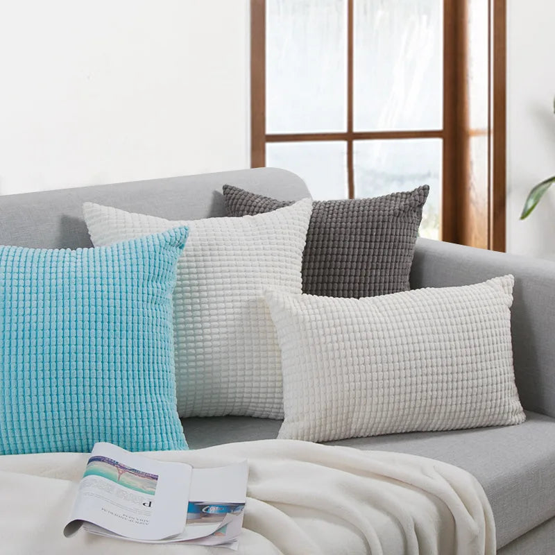 Gray sofa with textured throw pillows and a blanket in a living room setting.