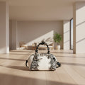 White handbag with black snake print and braided handle on a white background