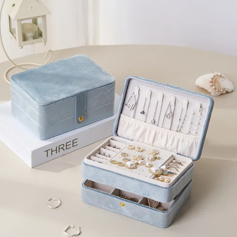 Open light blue jewelry box with jewelry inside on a white surface