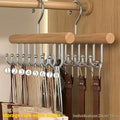 Wooden hanger with metal hooks holding belts against a wooden background