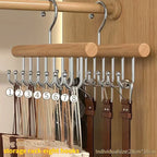 Wooden hanger with metal hooks holding belts against a wooden background