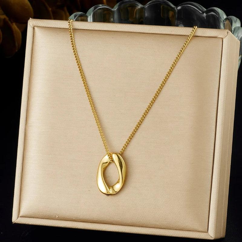 Gold necklace with a unique pendant on a beige display box.