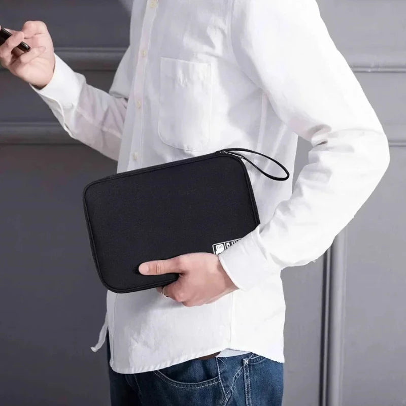 Person holding a black travel pouch with a visible brand logo against a neutral background