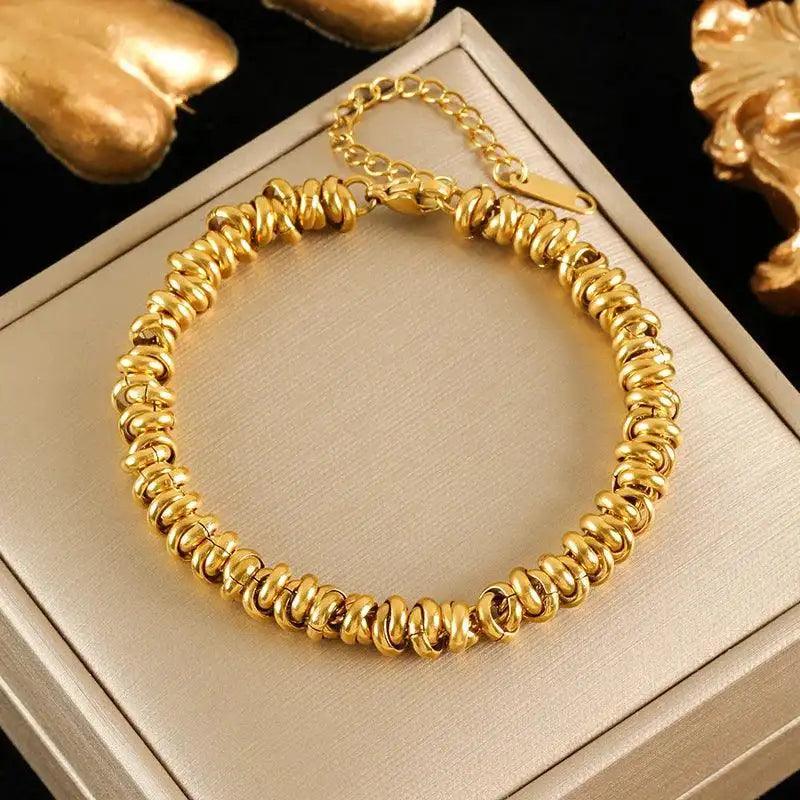 Gold bracelet on a beige jewelry box with gold earrings in the background