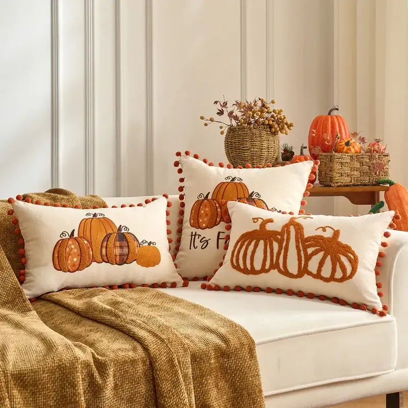 Decorative pillows with pumpkin designs on a couch in a cozy living room.
