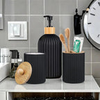 Black bathroom accessories set on a counter with a clock in the background
