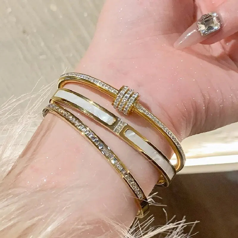 Gold bracelet with white stones on a wrist against a neutral background