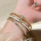 Gold bracelet with white stones on a wrist against a neutral background