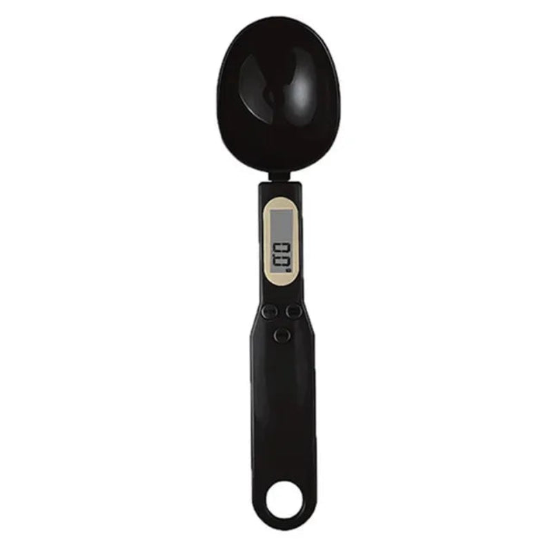 A digital kitchen measuring spoon in matte black plastic with an integrated LCD display showing '0.0' and a small beige accent ring, set against a plain white background.