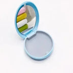 Compact mirror with colorful cotton swabs on a white background