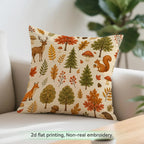 A square throw pillow with a woodland autumn pattern featuring trees, leaves, squirrels, foxes, and mushrooms on a cream background, styled on a light-colored sofa with a green plant in the background.