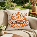 A square throw pillow with a fall autumn design sits on a beige outdoor sofa. The pillow features an orange pumpkin with a 'Welcome' banner, surrounded by orange and brown leaves on a cream background.