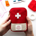 Red first aid kit with a white cross held by hands on a light background