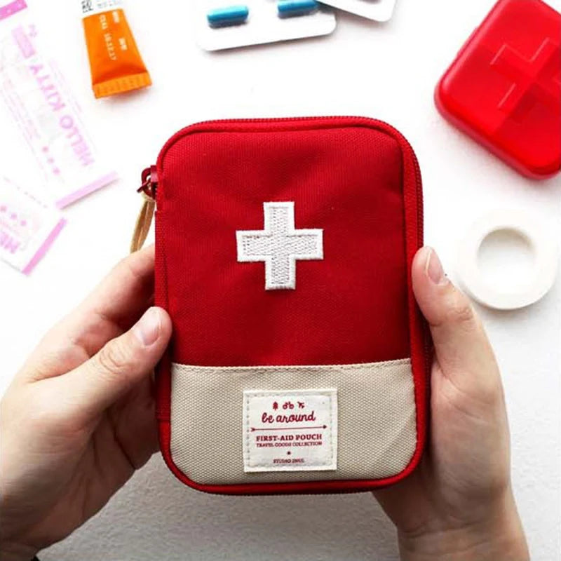 Red first aid kit with a white cross held by hands on a light background