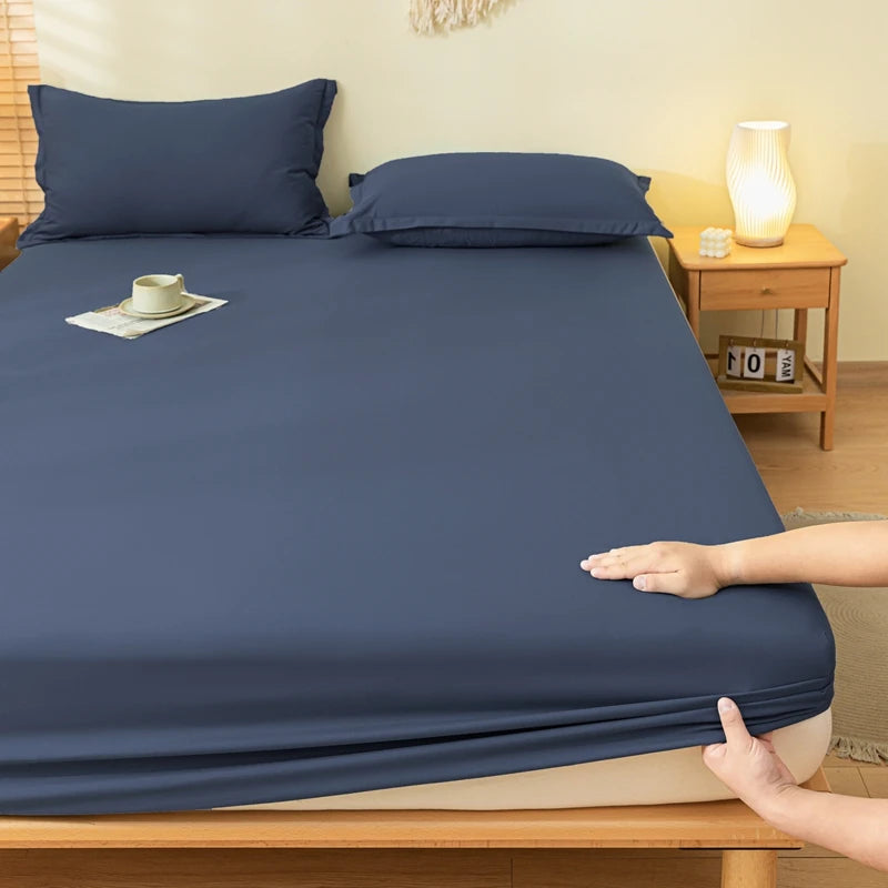 Person adjusting a navy blue fitted sheet on a bed in a bedroom setting.