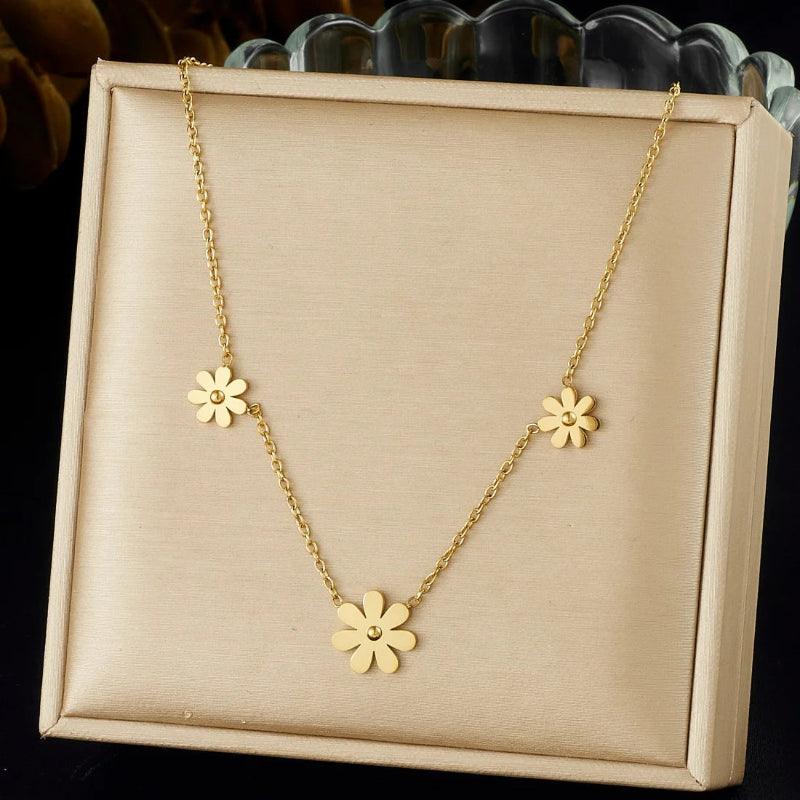 Gold necklace with flower pendants on a beige display box.