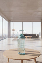 Clear water bottle with measurements on a wooden table in a cafe setting