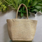 Woven straw bag on a textured surface with green plants in the background