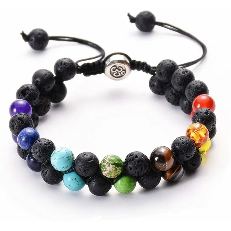A chakra bead bracelet made of black lava stone beads and colorful gemstone beads, featuring a silver-toned triquetra symbol charm on a white background.