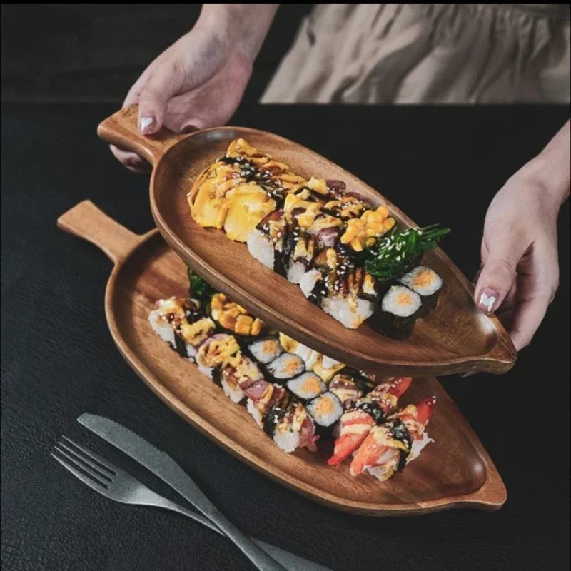 Wooden platter with assorted sushi held by two hands on a dark surface.